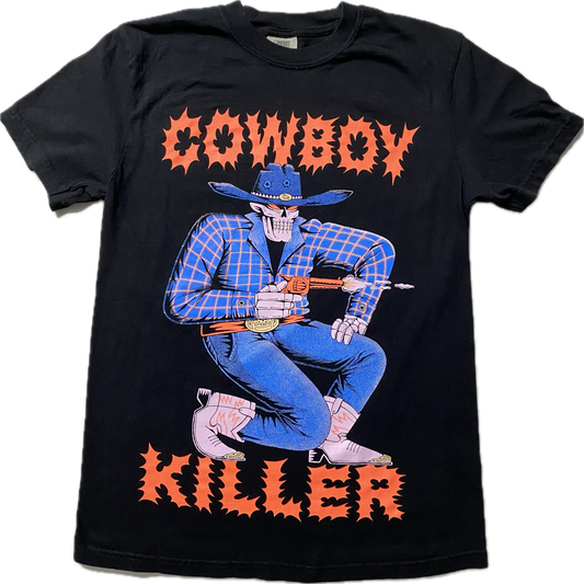 A black short sleeve t-shirt with the word Cowboy at the top and Killer at the bottom in a spikey font.  Between the words is a cartoon skeleton in blue cowboy attire and pink boots.