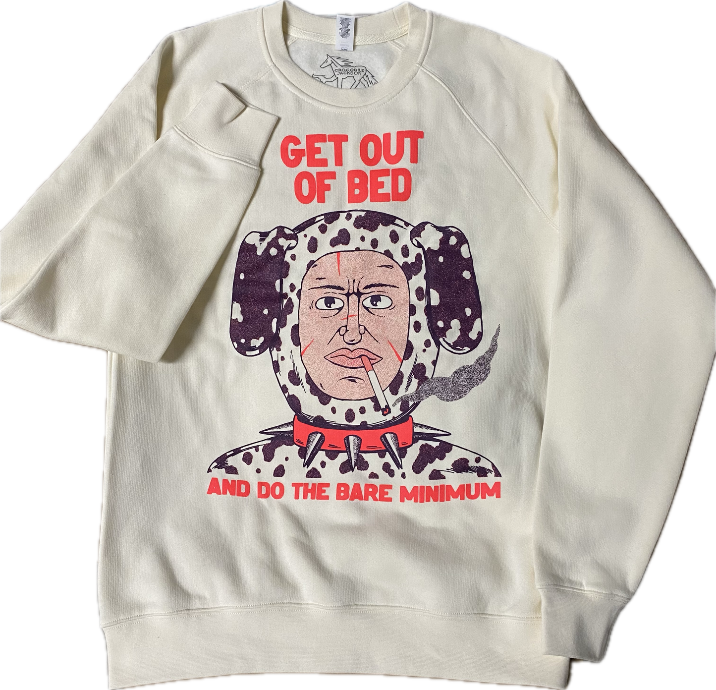 A cream colored sweatshirt with a cartoon bust of a guy in a Dalmatian dog costume. He has a lit cigarette in his mouth and a spiked red dog collar on. Above it reads GET OUT OF BED in red font and below it reads And Do The Bare Minimum.