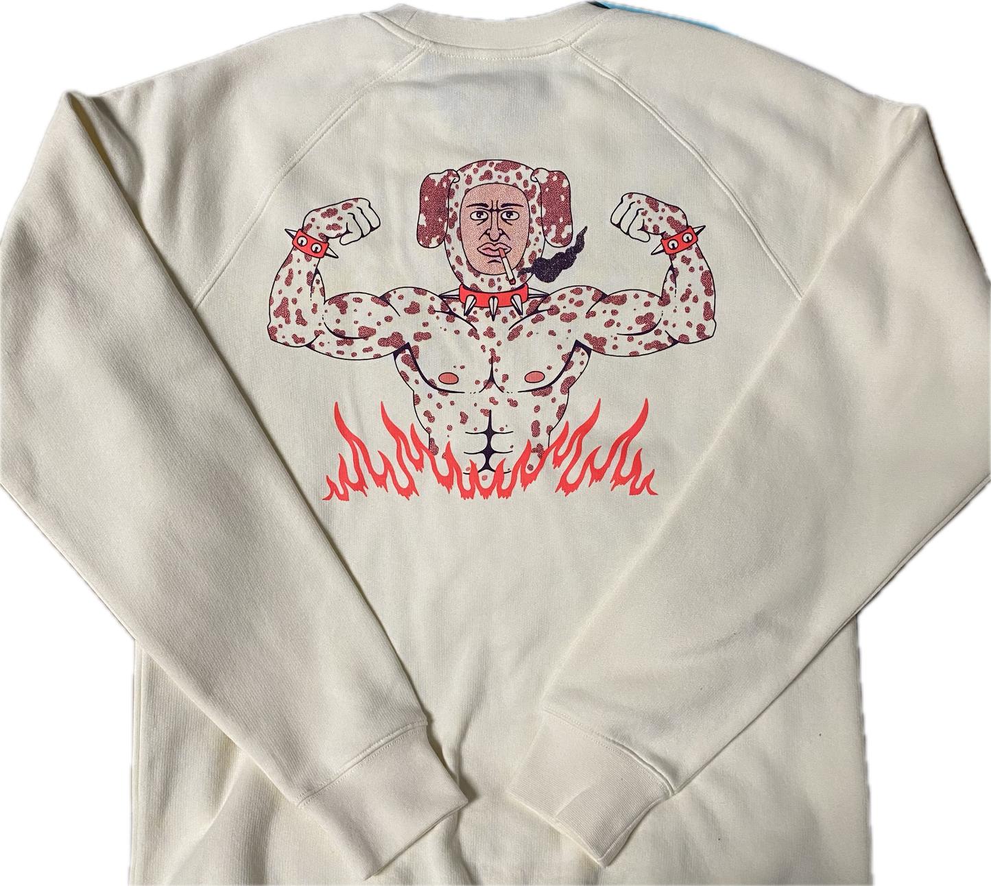 The back of a cream colored sweatshirt with a cartoon body builder in a Dalmatian dog costume showing from the waist up. He has is arm out flexing his muscles and is wearing a red spiked dog collar around his neck and wrists. He is smoking a cigarette.