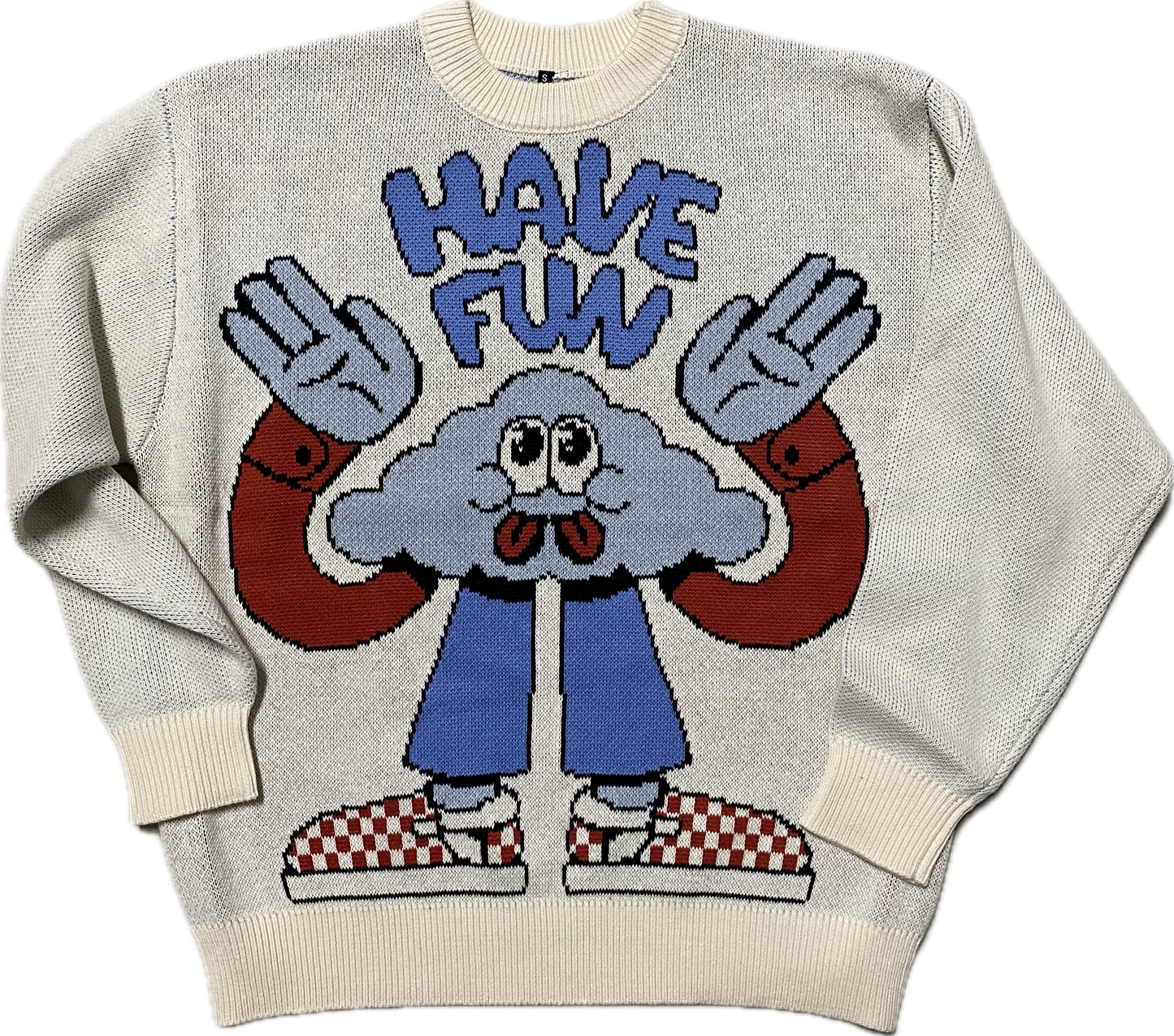 A light blue knitted sweater that reads "have fun" in blue puffy font at the top.  Below the words is a cloud cartoon character with googly eyes and 2 tongues.  It is holding it's arms up that have red long sleeves.  It is wearing blue pants and red and white checkered tennis shoes.