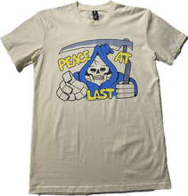 Cargar imagen en el visor de la galería, An off white t-shirt with a cartoon skeleton in a blue cloak printed on the chest area of the t-shirt.  A sickle over the head of the skeleton  and it reads Peach at Last in gold puffy font.
