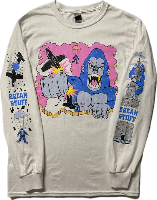 A white long sleeve t-shirt with a cartoon blue gorilla punching a black plane.  Behind the gorilla is the ejected pilot.  On the right sleeve it reads Break Stuff in blue font with a black broken plane above it and a parachuting pilot below it.  On the left sleeve is a blue gorilla climbing a high rise building and it reads Break Stuff too.