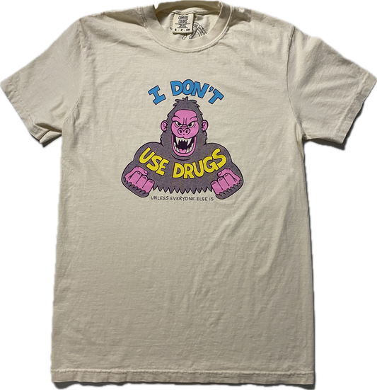 An off white short sleeve t-shirt with an angry purple cartoon gorilla with clinched fists and fangs..  It reads I Don't in blue font then Use Drugs in gold font.  In tiny font at the bottom it reads Unless Everyone Else Is.