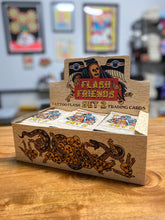 Cargar imagen en el visor de la galería, A box of trading cards that are called Flash Friends Set 2.  The box is cream colored with artwork of skulls, a snake and the grim reaper.  The box is on a wood table and the background is blurred.
