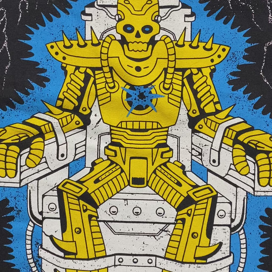 A video of the a black short sleeve tee that reads Feel something at the top with silver color and lighting around it. Below the words is a cartoon skull robot in gold that is strapped in an electric chair. Between it's feet is a gold mouse coming out of the bottom of the chair. Crocodile Jackson signature at the bottom.