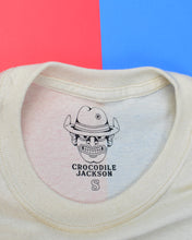 Cargar imagen en el visor de la galería, Label on the inside of the shirt features the outline of the Crocodile Jackson Cowboy logo wearing a hat with the brim flipped up &amp; a bullet hole through the crown. Below is &quot;Crocodile Jackson&quot; in a black western font. Below this is the size of the shirt in the same font, but in outline. Photographed is a size small so a capital letter S is shown.
