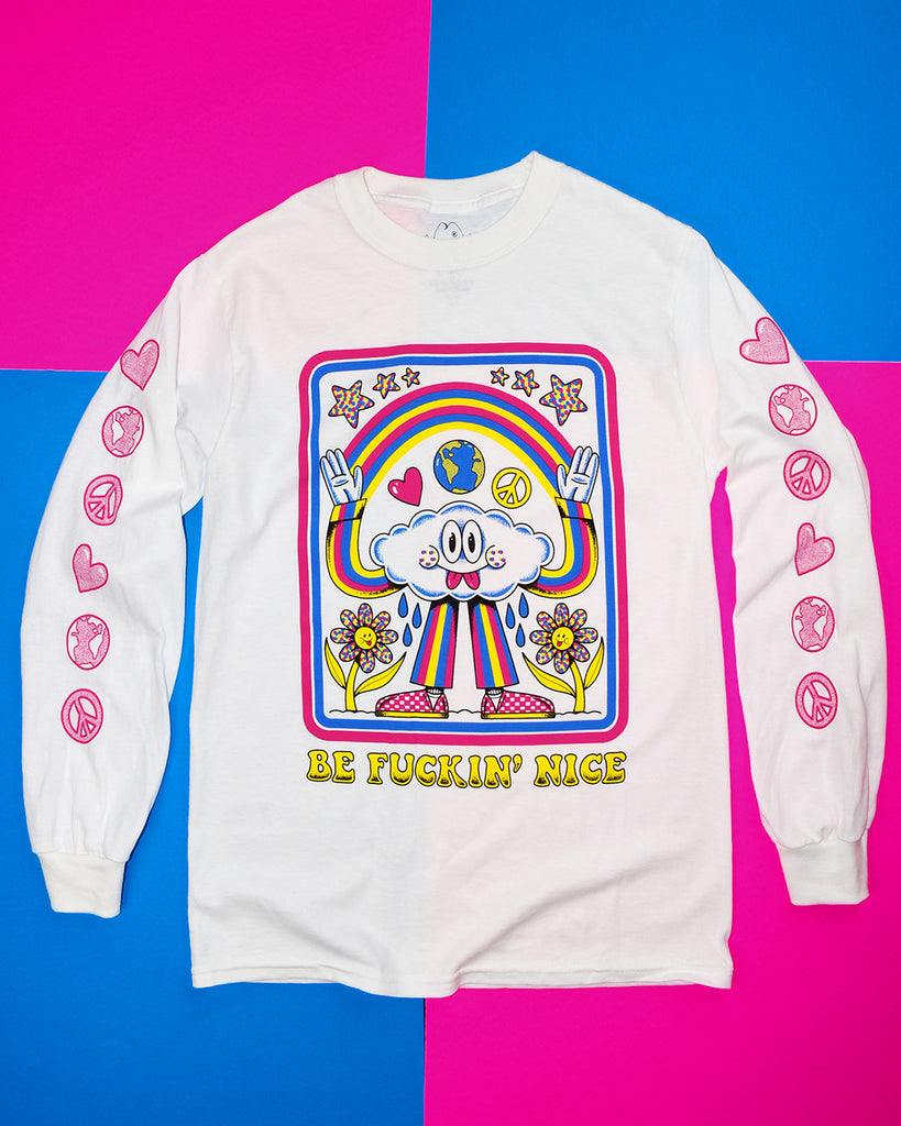 White long sleeve with the words “Be Fuckin’ Nice” in yellow retro font at the bottom and a cloud character wearing a blue, pink, and yellow striped pantsuit with pink checkered sneakers. The cloud is grinning with 2 tongues sticking out, casting a rainbow between his raised hands with water drops below the armpits watering the 2 yellow and polka dot flowers below his arms. Heart, globe, and peace sign are between the cloud head and the rainbow, 6 polka-dotted stars are above the rainbow.