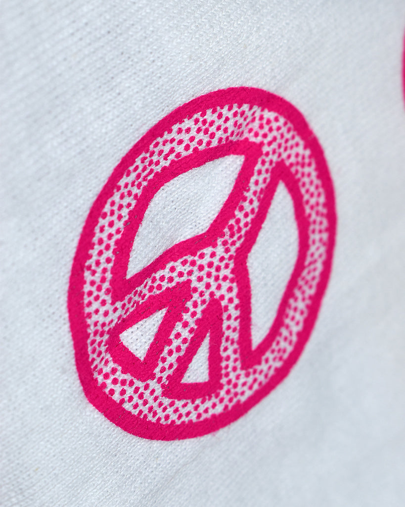 Close-up of one of the designs on the sleeve: of the peace sign. The design is a thick peace sign with bolded edges and dots within these borders. The designs are hot pink.
