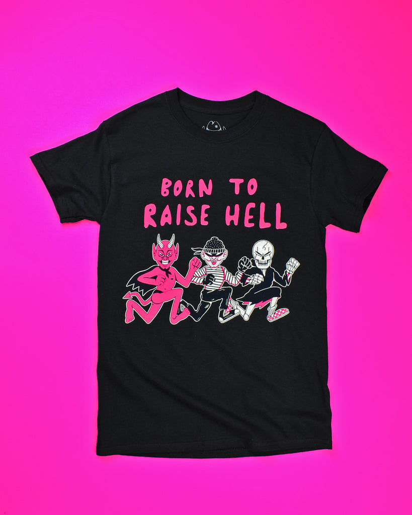 A black short sleeve t-shirt with Born to Raise Hell printed in a pink puffy font. There are 3 characters in a mid run pose below the wording. The first character is a pink devil with a black cape and thong. The 2nd character is a thief w/a black polka dot bandana, black eye mask, black/white striped long sleeve shirt, black pants and high top black sneakers. The 3rd character is a skeleton with a black robe, white socks and pink/white checkered sneakers.