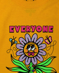 Gold short sleeve t-shirt that reads Everyone is Cute (except for you) in pink font. The (except for you) is in a very small font. In the center is a large flower with a thorny green stalk and 6 flailing leaves. The flower petals are blue, pink and white confetti and the yellow center of the flower has googly eyes round cheeks and a pink double tongue sticking out. On either side of the top of the flower is a flying bee and butterfly.