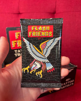 A close up of a person holding a pack of trading cards..  The package reads Flash Friends in gold letter on a red background.  A cartoon eagle is below the words.  The eagle is in a landing position with its claws out.  Behind the hand is the box for the cards and behind that is red fabric.