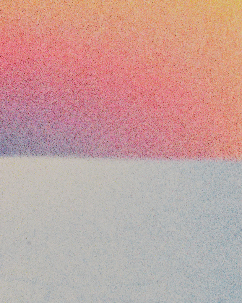 Closeup of the risograph print. The focus is on the intersection of the ocean and the sky, where a very light blue color of the ocean meets the blue, purple, red, and yellow gradient of the sunset. There is a grainy effect across everything.