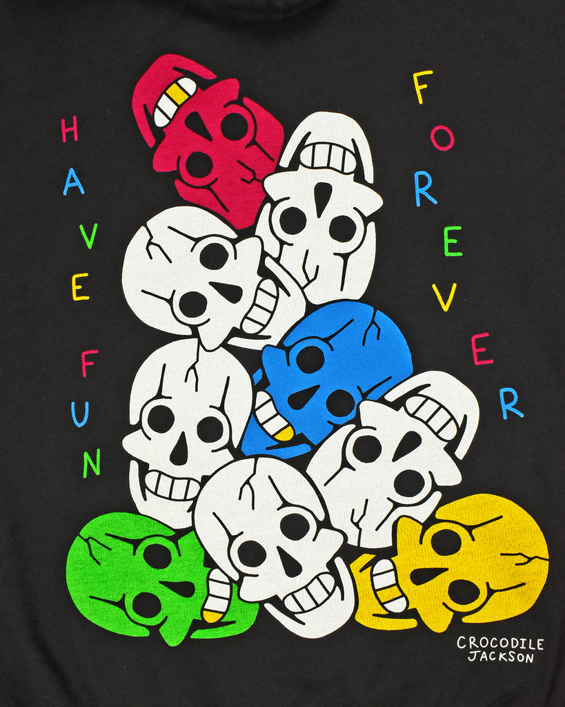 A close up of the back of the black hoodie artwork with 9 colorful screen printed smiling skulls piled high. On the left and written vertically is Have Fun in alternating colors of red, blue green & yellow. On the right and also vertically is Forever in the same alternating colors per letter.