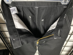 A picture of a black pair of pants (front view) hung on a black wire mesh background.  The top stitching is white.  The pants are opened up to see the inside and the logo tag.