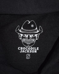 Close-up image of the screen-printed clothing tag of the hoodie, featuring the Crocodile Jackson cowboy logo, the words "Crocodile Jackson" in all caps, and the clothing size symbol (S for Small).