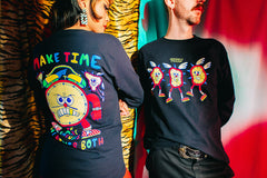 Model on left in a black long sleeve t-shirt that reads Make Time at the top in alternating red, gold, green and blue letters. A giant frowning clock is in the middle with red arms and legs wearing socks and red checkered tennis shoes.  At the bottom it reads Or Make Excuses But Never Both in the same alternating colors. Model on the right in a black long sleeve t-shirt with 3 smiling cartoon clocks on the front that all have spikes, wings, legs and checkered tennis shoes.