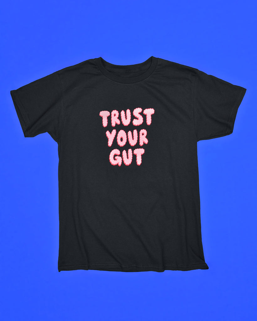 Black t-shirt with the words Trust Your Gut printed in the center in pink puffy letters.