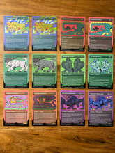 Load image into Gallery viewer, A wood table with 12 trading cards.  Half the cards are shimmery and the others are not.  Each card has a cartoon animal and all part of the Magic the Gathering Secret Lair game by Hasbro.
