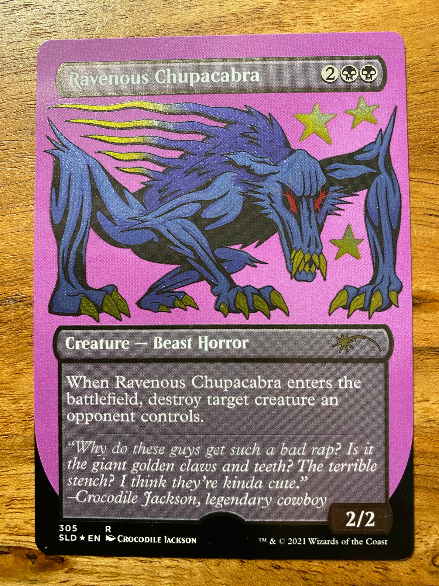 A shimmering trading card with a title at the top that reads Ravenous Chupacabra. Below that is a blue cartoon creature with red eyes and gold fangs and claws. Below the creature is the card information for the game - Magic the Gathering.