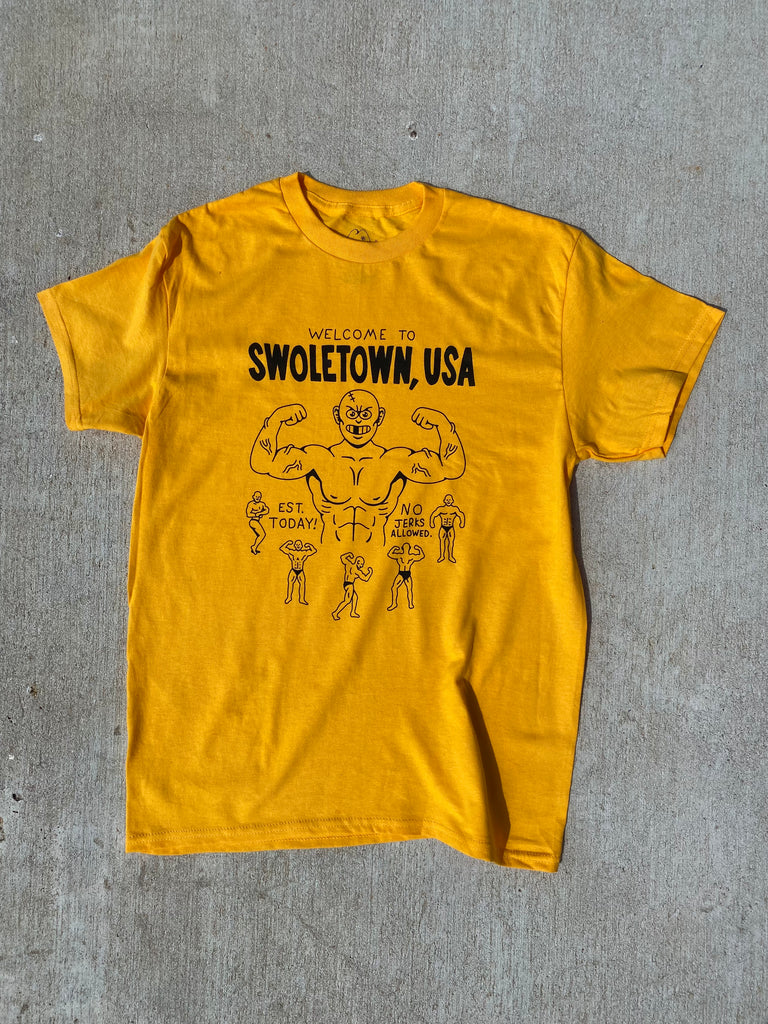 A yellow short sleeve t-shirt that reads Welcome to Swoletown, USA, est. today! and No Jerks Allowed.  In the center is a cartoon body builder flexing his muscles.  His veins are popping out and he has no hair stitches on the top of his head.  Around the bottom are various poses of the same body builder.