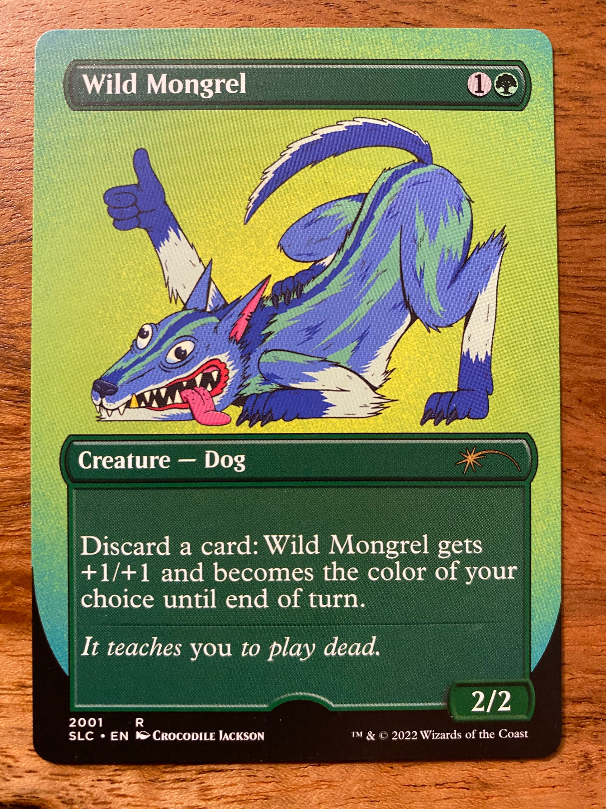 A trading card that has an image of a blue, green and white cartoon dog in a playful position with it's butt in the air. The right paw is extended in the air with a thumbs up. The title at the top of the card reads Wild Mongrel.