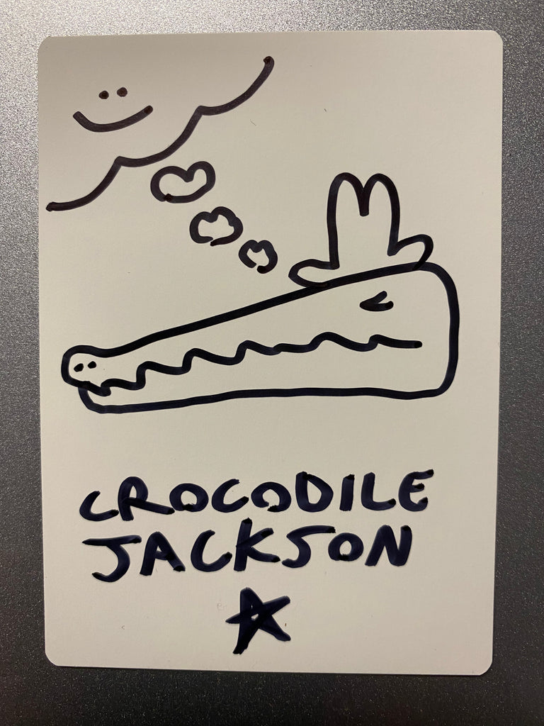 The back of the trading card that is all white where the artist has hand drawn a sleeping crocodile head with a cowboy hat dreaming.  In the top left corner is a smiling cloud.  At the bottom is the artist signature - Crocodile Jackson with a star below it.  All done in black marker.