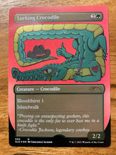 Load image into Gallery viewer, A trading card that shimmers in the light with a title of Lurking Crocodile.  Below the title is a cartoon crocodile with his tail overhead and a cowboy hat sitting on the end of it's tail.  The left arm of the crocodile is holding a knife and has a heart tattoo that reads 'Croc' on the top of it's arm.  Below the art is information on Hasbro's Magic the Gathering game.
