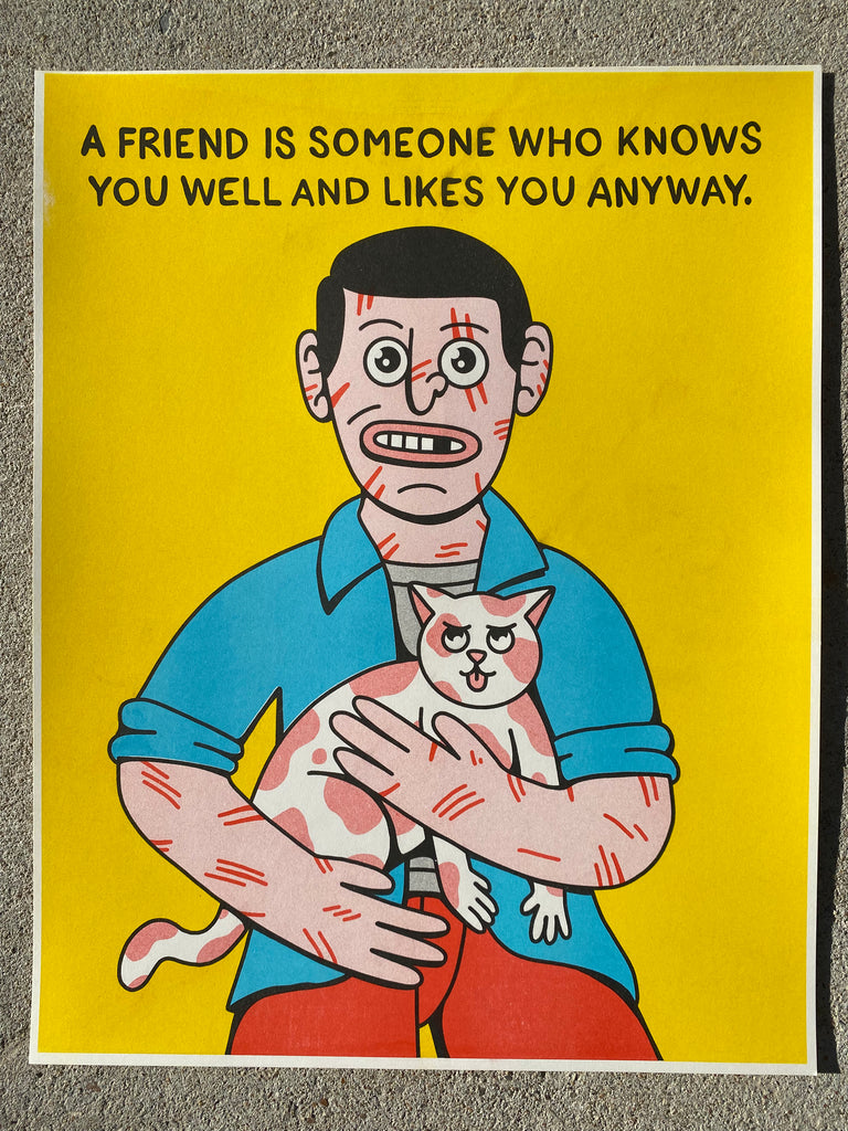A poster with a yellow background that has a cartoon man holding a white and tan cat and the man has scratches all over his face and arms.  The man has black hair and he is wearing a blue shirt and red pants.  At the top is reads "A Friend is Someone Who Knows You Well and Likes You Anyway".
